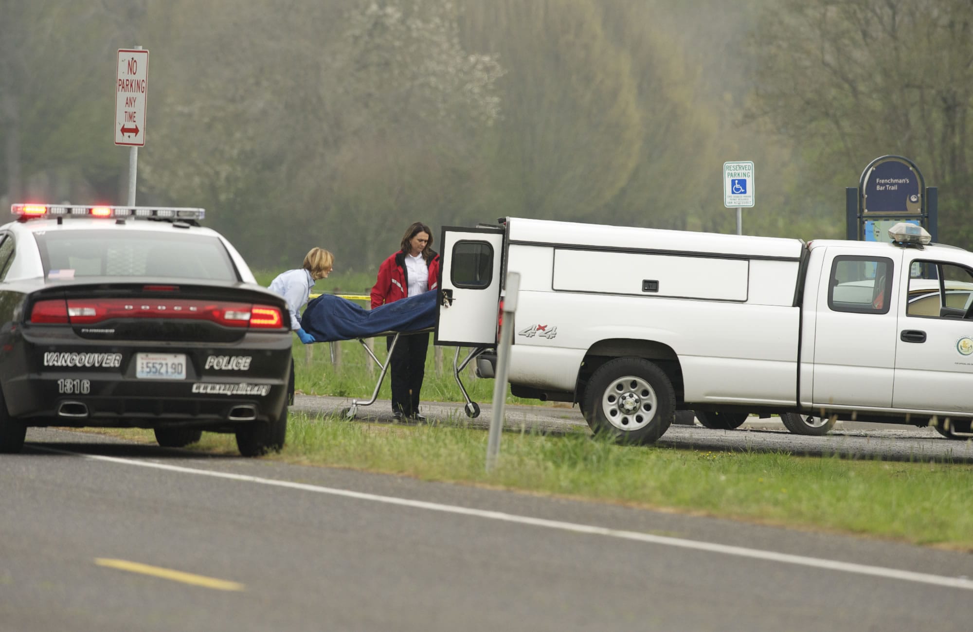 A dead body found inside a smouldering car is removed from the scene near Vancouver Lake on Monday.