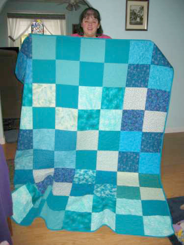 Burnt Bridge Creek: Jeanne LaViollette displays one of the quilts made by the Caritas Quilts.