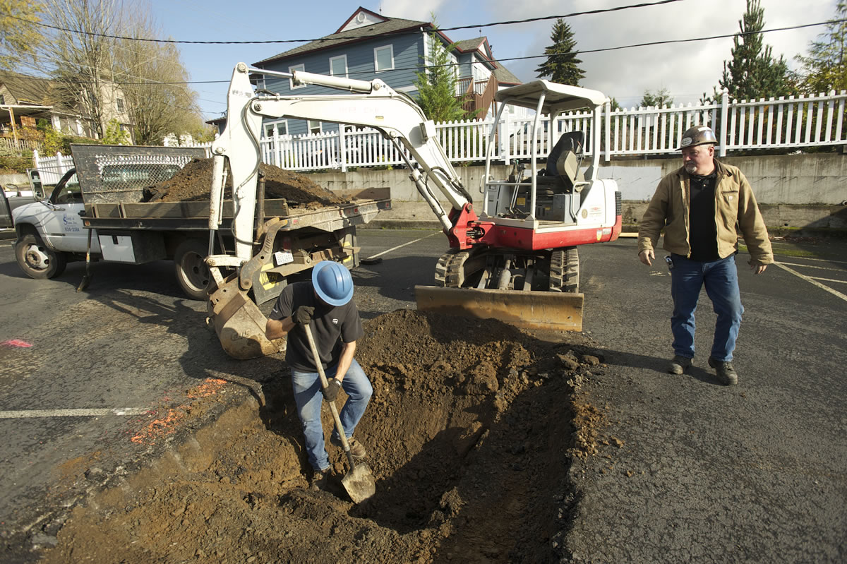 Photos by Steven Lane/The Columbian
Ryan Boyle, left, and Jim Haag from Haag and Shaw Co. repair a sinkhole in a Camas parking lot.