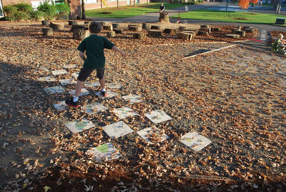 Hough Elementary School third-grader Andy Kleiner hops along tiles painted by his peers in the school's new &quot;Backyard Field Trip&quot; outdoor area.