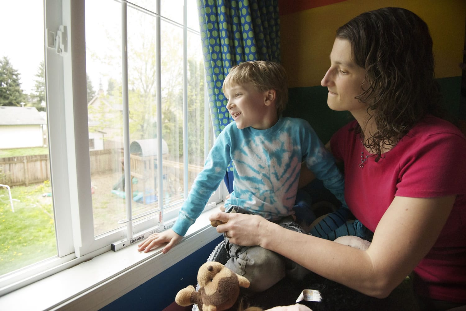 Thomas Keen Cunningham, 6, looks out his bedroom window as he is held by his mother, Becca Keen Cunningham. Thomas suffered life-threatening injuries when he fell from the window in 2010; through aggressive and extensive therapy, he has recovered.