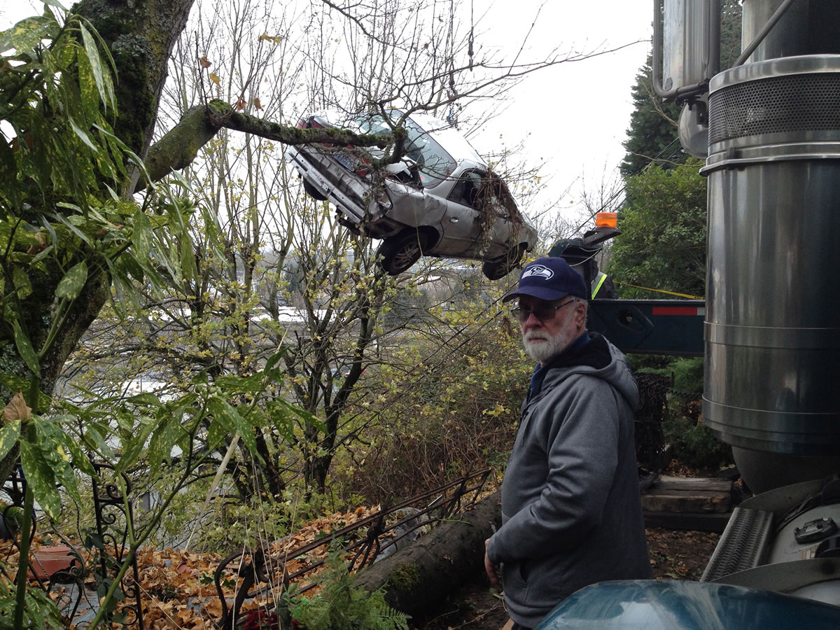 Andy Matarrese/The Columbian Jim Morrison watches as a towing company&#039;s crane hoists a car from down the hill below his house. The car crashed into an apartment building below Tuesday night after it hit an embankment beneath Morrison&#039;s home, went airborne then down the hill on the far side.