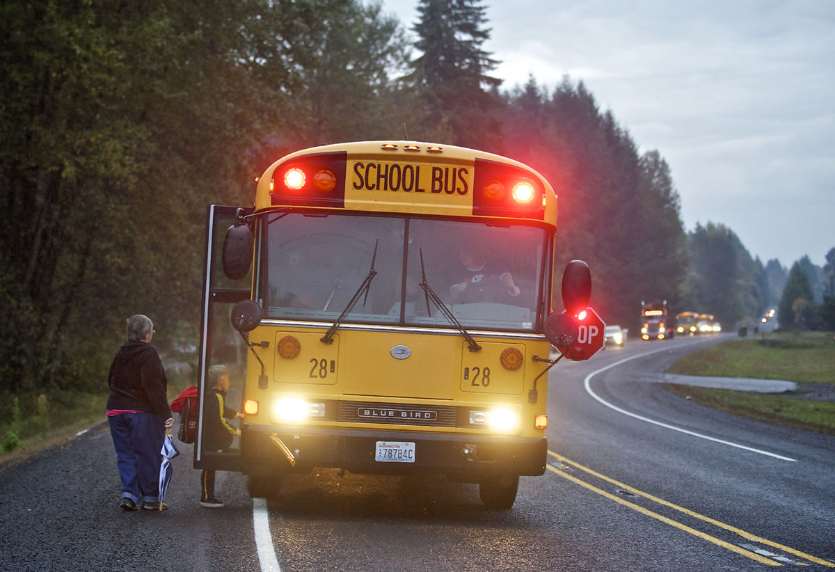 Sharon Norton watches her grandson, 6, board a Woodland School District bus driven by Jolleen Washburn on Friday as traffic stops on Lewis River Road.