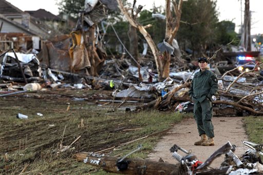 A member of a security team helps guard an area of rubble from a destroyed residential neighborhood, one day after a tornado moved through Moore, Okla., Tuesday, May 21, 2013.