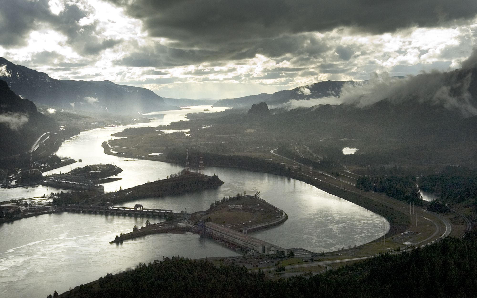 This aerial photograph of the Columbia River Gorge from 2006 shows the view looking west with Bonneville Dam in the foreground.