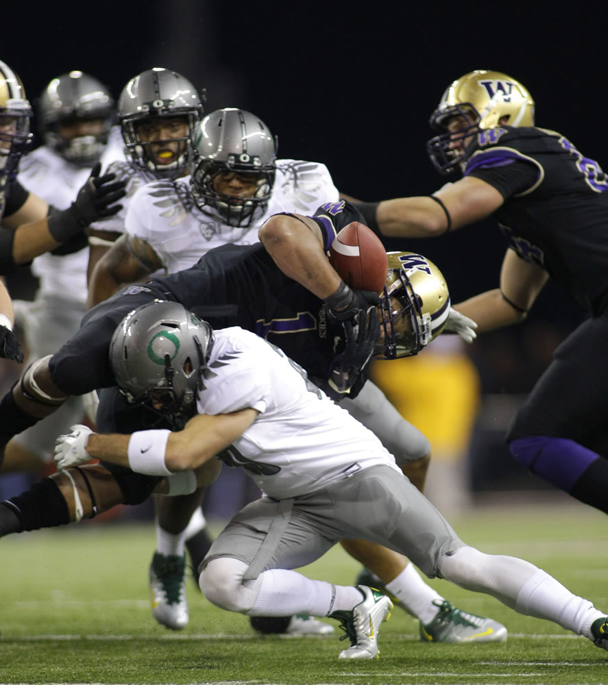 Washington's Chris Polk barely holds on to the football as he runs against the Oregon defense in the first half Saturday.
