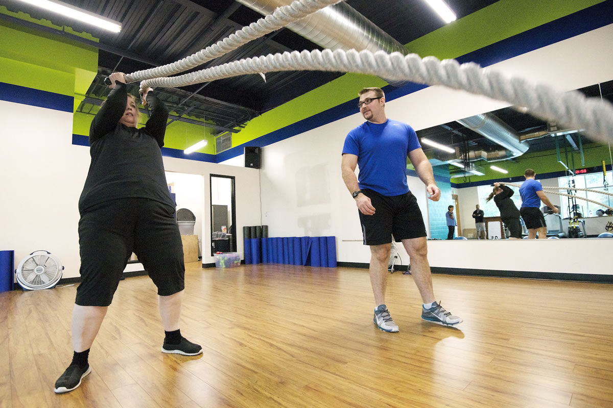 Laina Harris performs a resistance workout as fitness trainer Cody Sorensen gives instruction during a personal training session Thursday at Body Design Fitness in Camas.