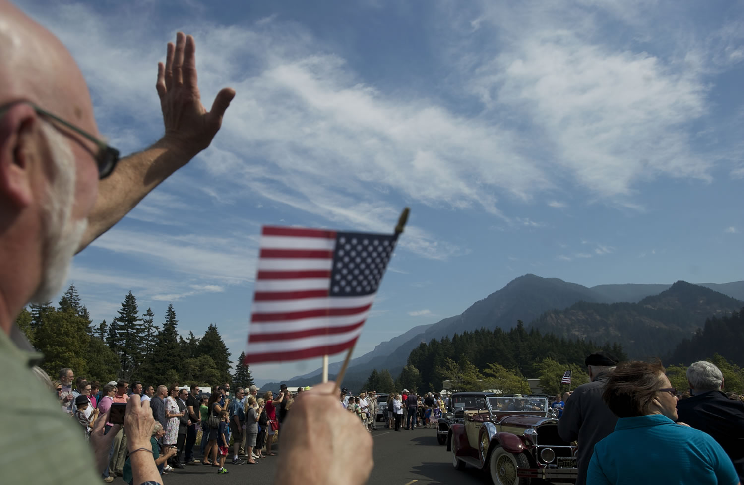 John Adams of Ocean Park, Ore., waves at a passing parade of 1930s-era cars carrying federal officials, politicians, tribal leaders and visitors to mark the 75th anniversary of the dedication of the Bonneville Dam on the Columbia River.