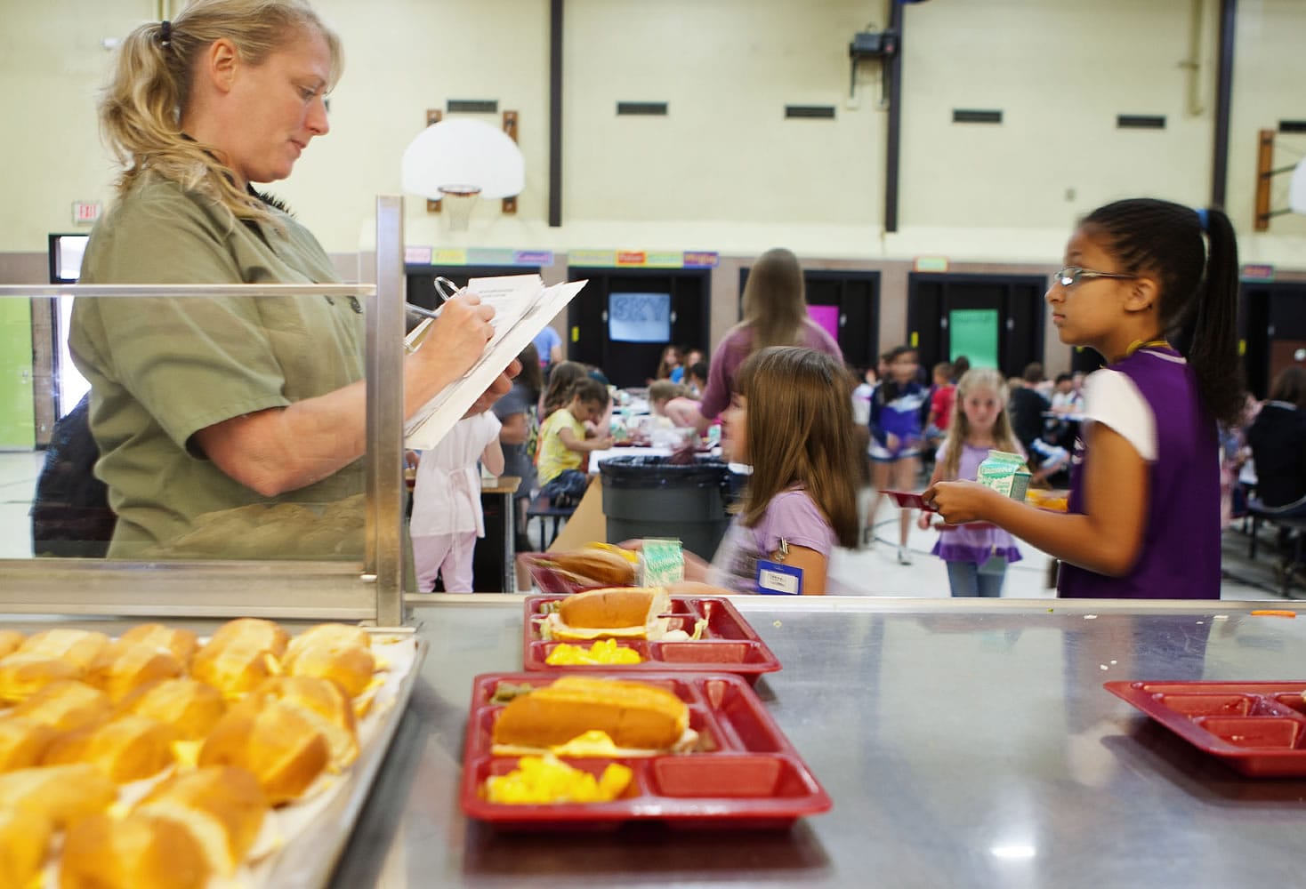 Share volunteer Kari Barnes marks off the daily meal count as children pass through the lunch line at Silver Star Elementary.