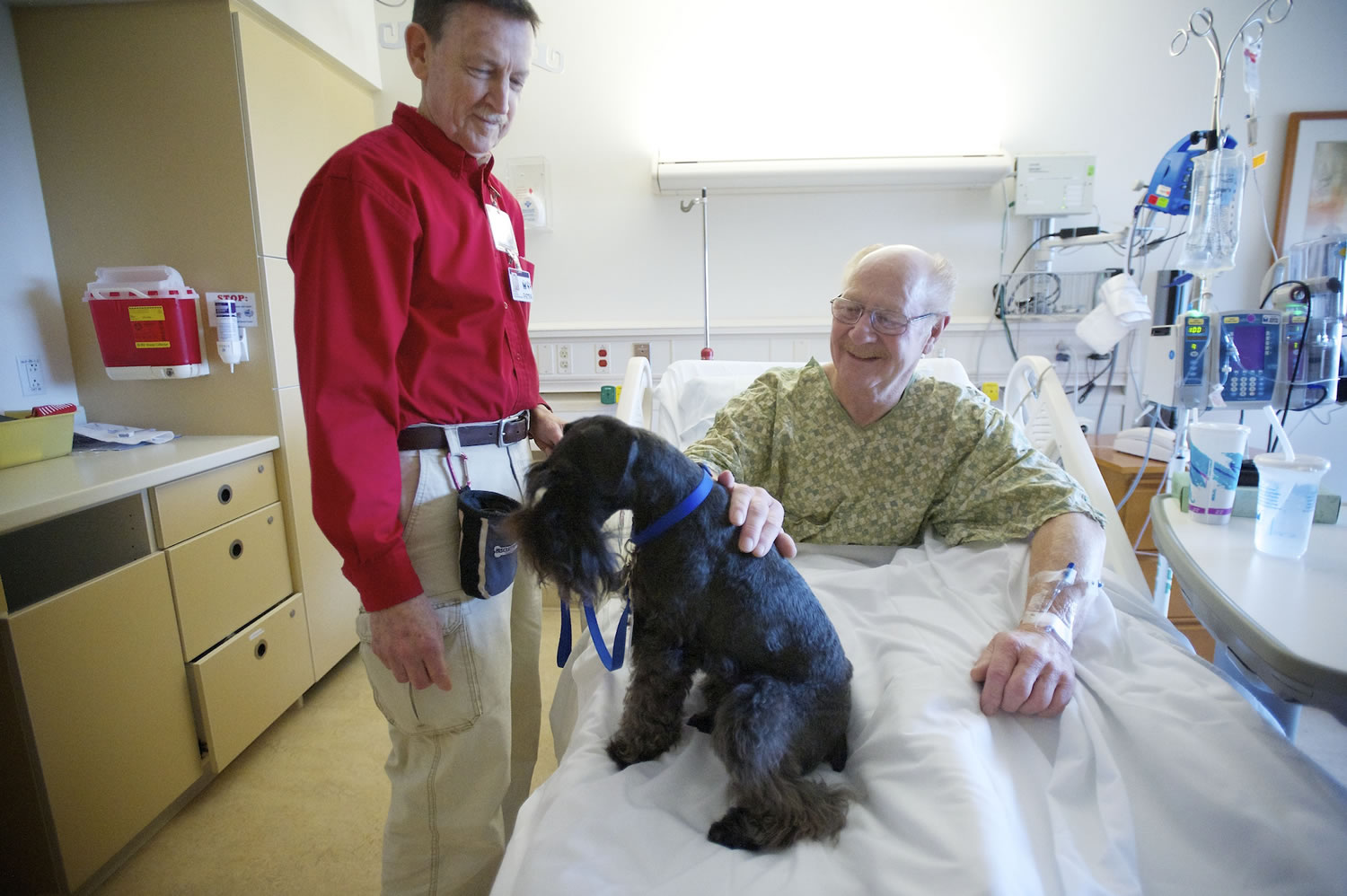 Legacy Salmon Creek Medical Center volunteer Peter Christensen, left, and his therapy dog, Mukaluka Dirtypaws, visit with Cougar resident Bob Wenzel, who was preparing to undergo surgery.