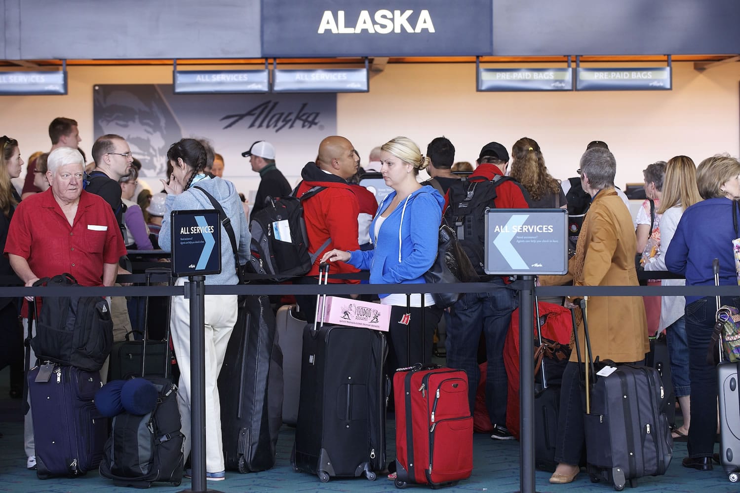 Commuters wait in long lines to check in at Alaska Airlines on Monday at Portland International Airport.