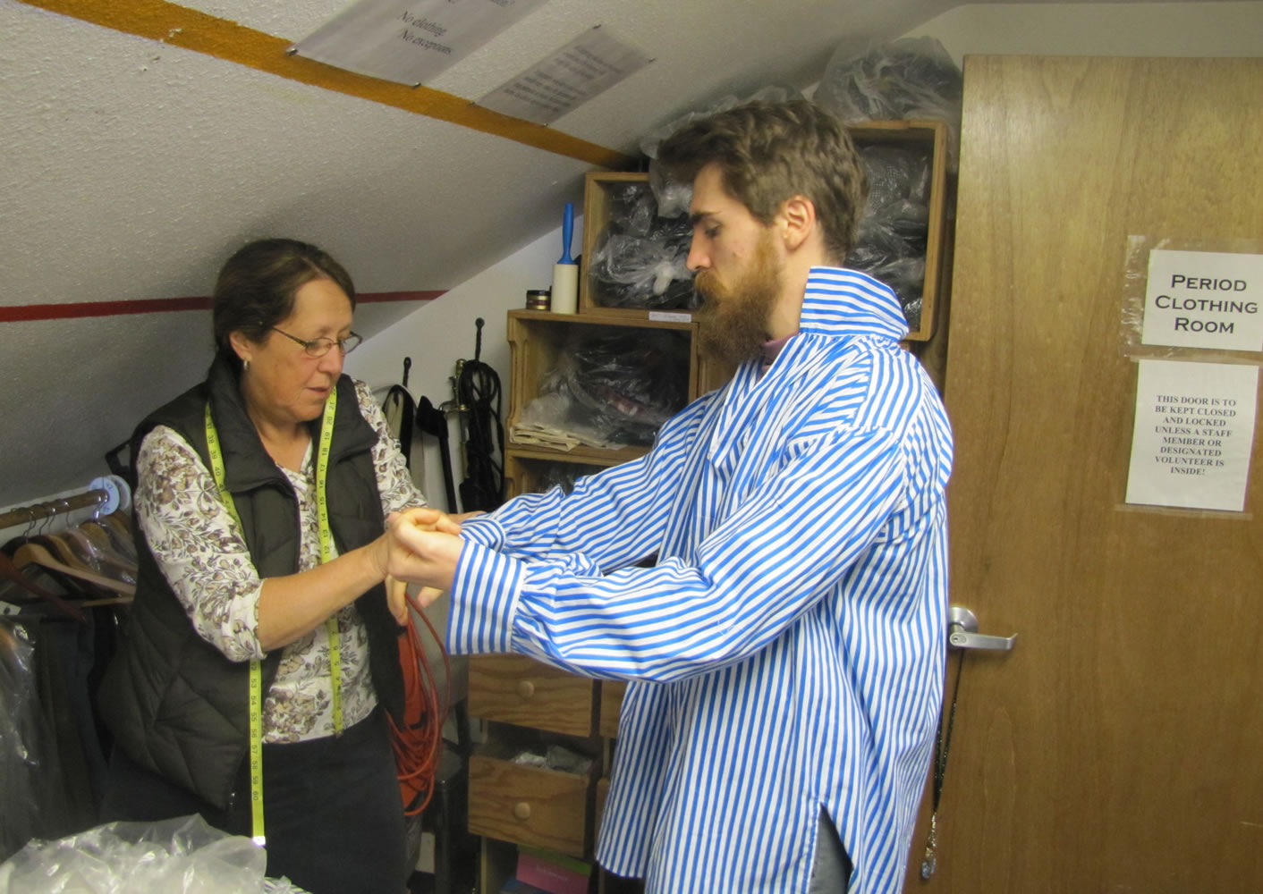 Sheila Dolle checks the fit as re-enactor Ethan Hardy tries on a shirt.