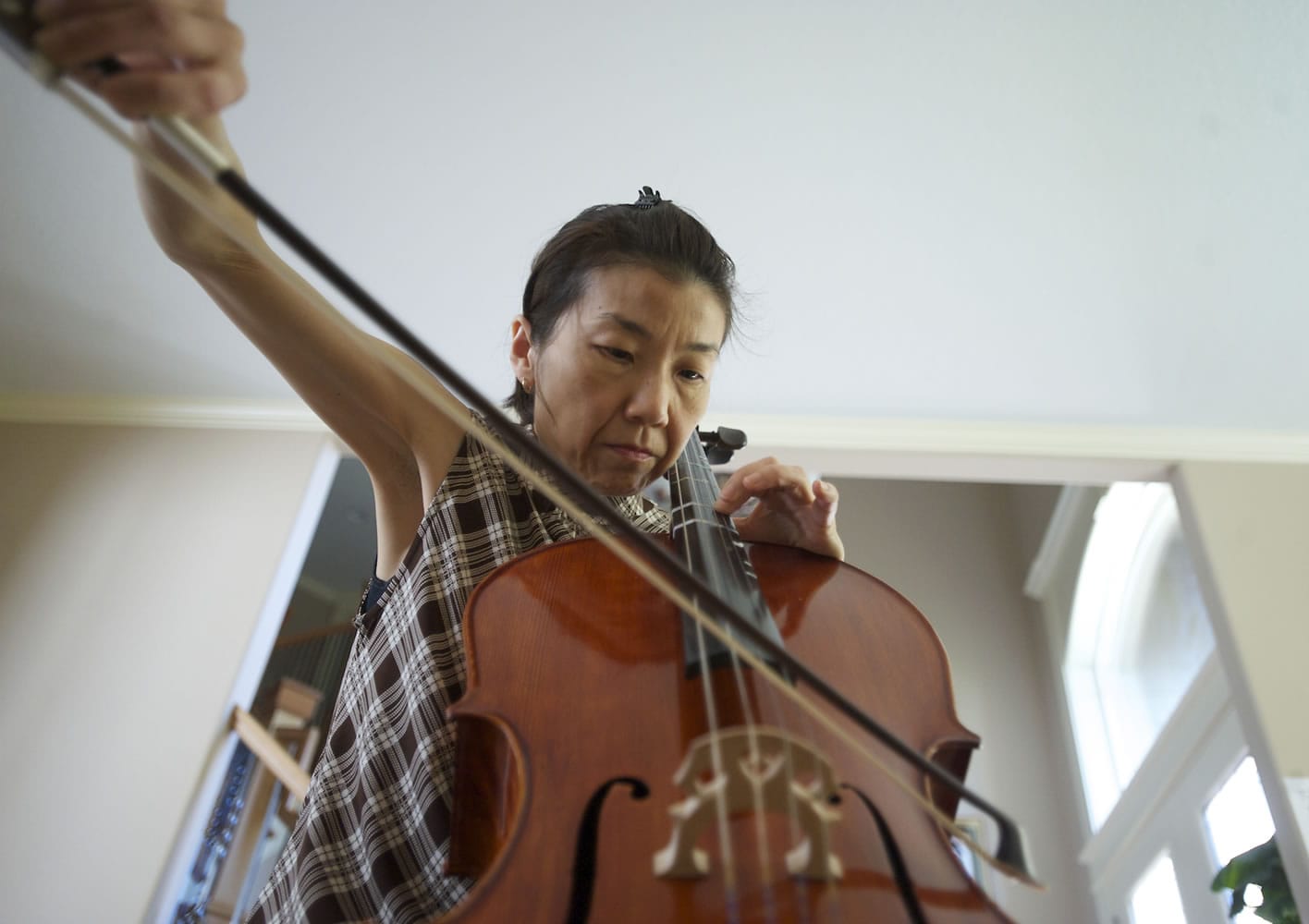 Akemi Noll, who was diagnosed with early-onset Parkinson's six years ago, practices the cello at her east Vancouver home Wednesday.