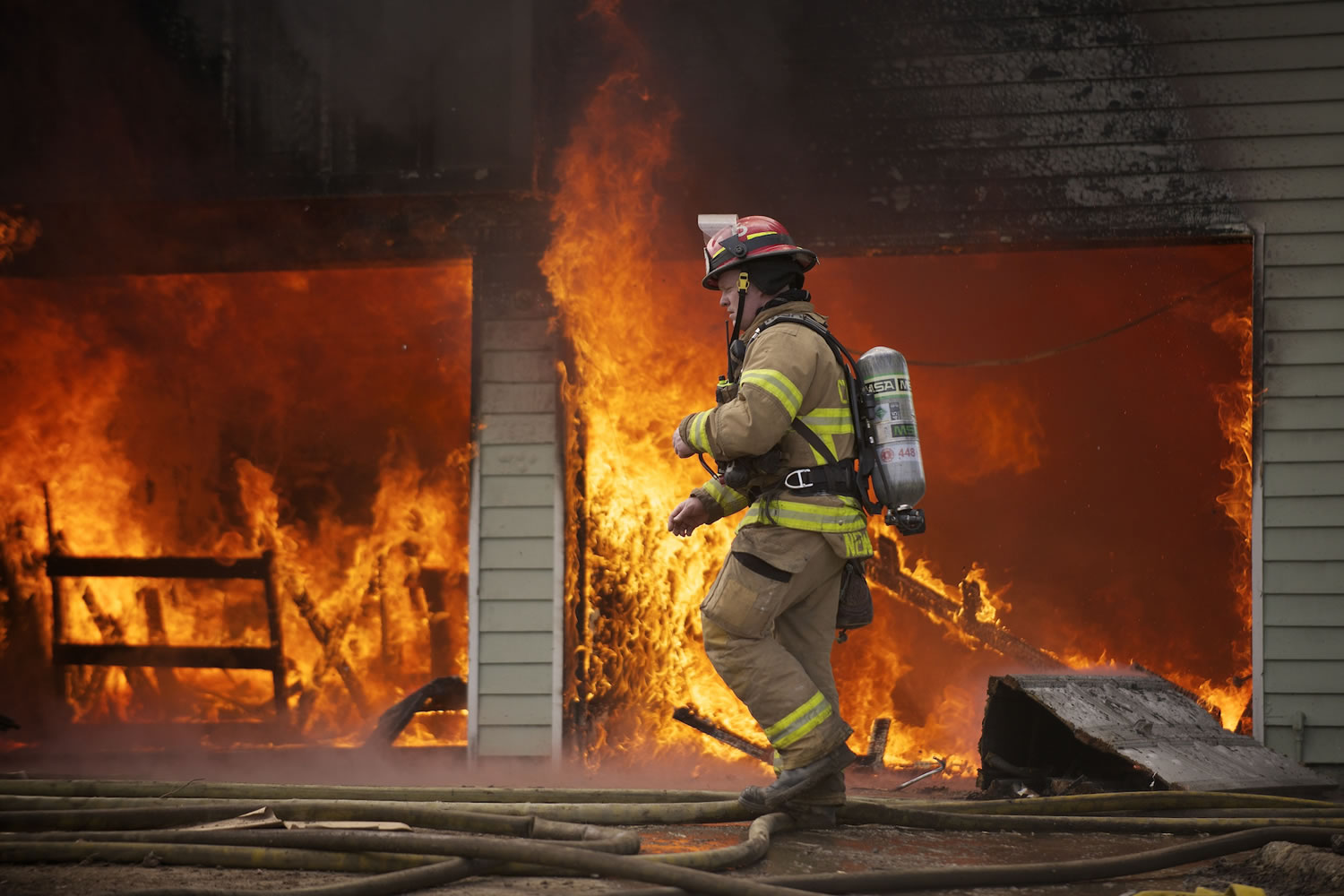 Assistant Fire Chief Shawn Newberry walks by a burning garage last week at the first of two training fires.