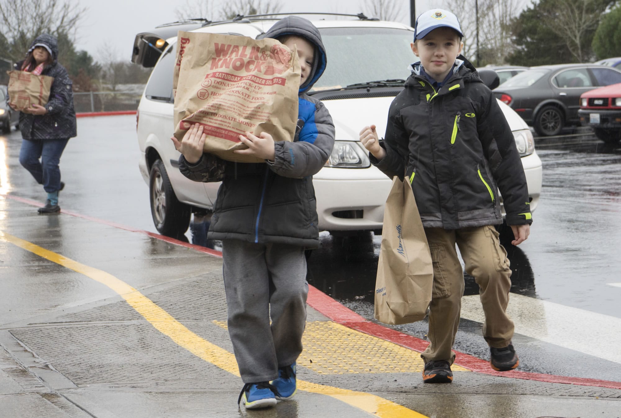 Dante Breeding, 5, left, and Gabriel Breeding, 8, haul bags of food from their van to the Walk &amp; Knock drop-off site at Orchards Elementary School. They were among about 3,700 Clark County residents who volunteered for the annual event Saturday.