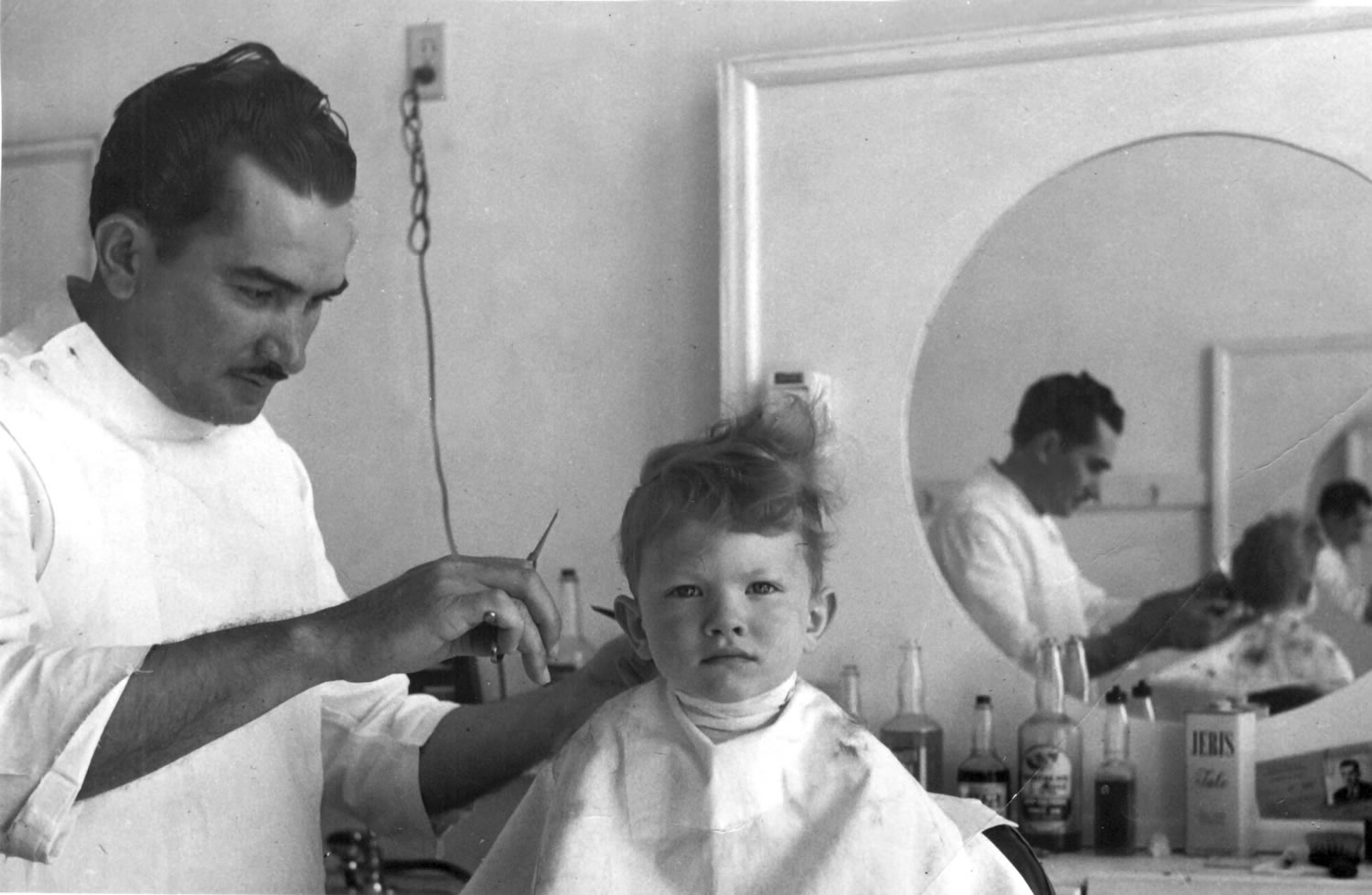 Cecil Wright cuts the hair of a boy whose last name is Potter in August 1947.