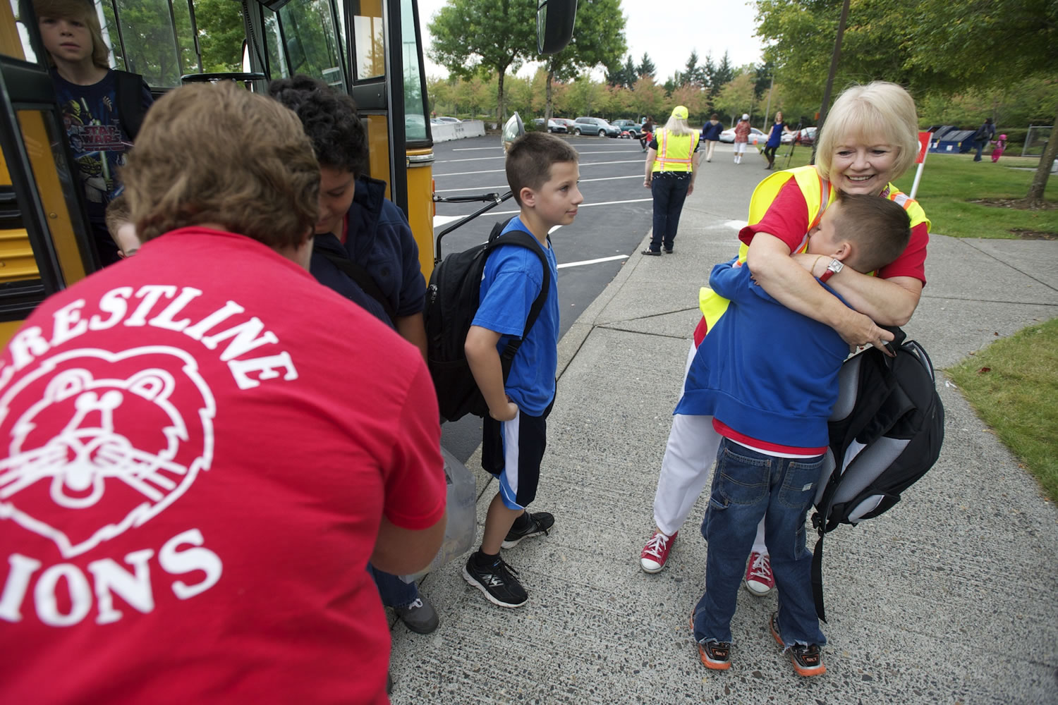 Jane Olschewsky gives returning 5th grader Josh Krzysiak, 10, a big hug as he gets off the bus on the first day of school at the temporary Crestline Elementary today.