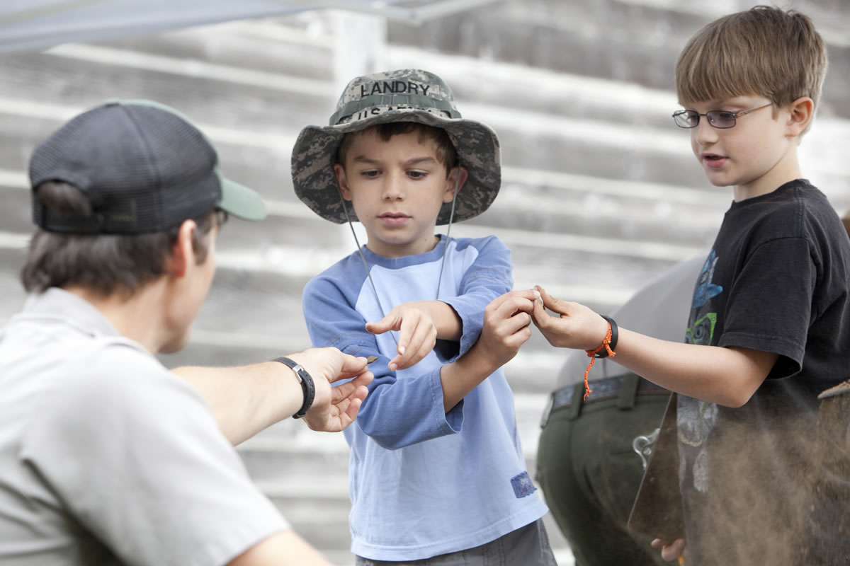 Landry Smith, 9,  center, hands an item to Palmer Prager, 10, right, during a mock archaeology dig at Fort Vancouver on Saturday morning.