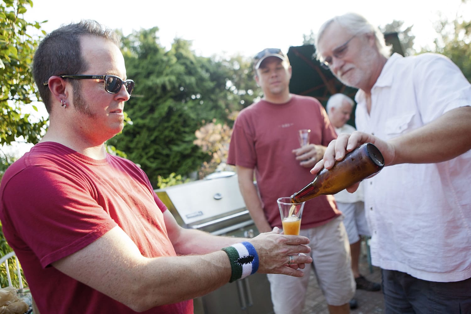 Carter Park resident Gary Kokstis pours a glass of home-brewed beer for neighbor Jerrad Isch during a gathering of the informal 29th Street Brewers Guild in Kokstis' backyard garden.