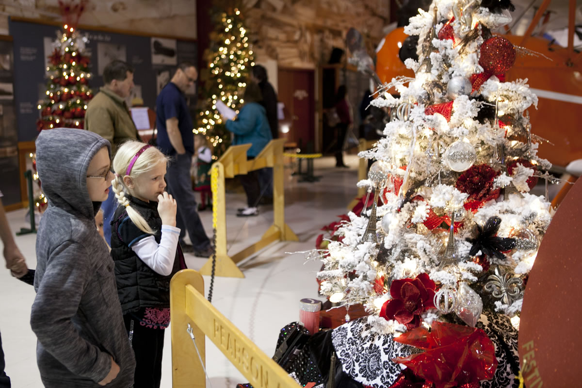 Photos by Vivian Johnson/for The Columbian
Cole Stokes, 8, left, and his sister Calista, 6, take in a Parisian-themed Christmas tree -- with shining fleurs-de-lys and Eiffel Towers -- during a Saturday visit to the Festival of Trees at Pearson Air Museum with their family.