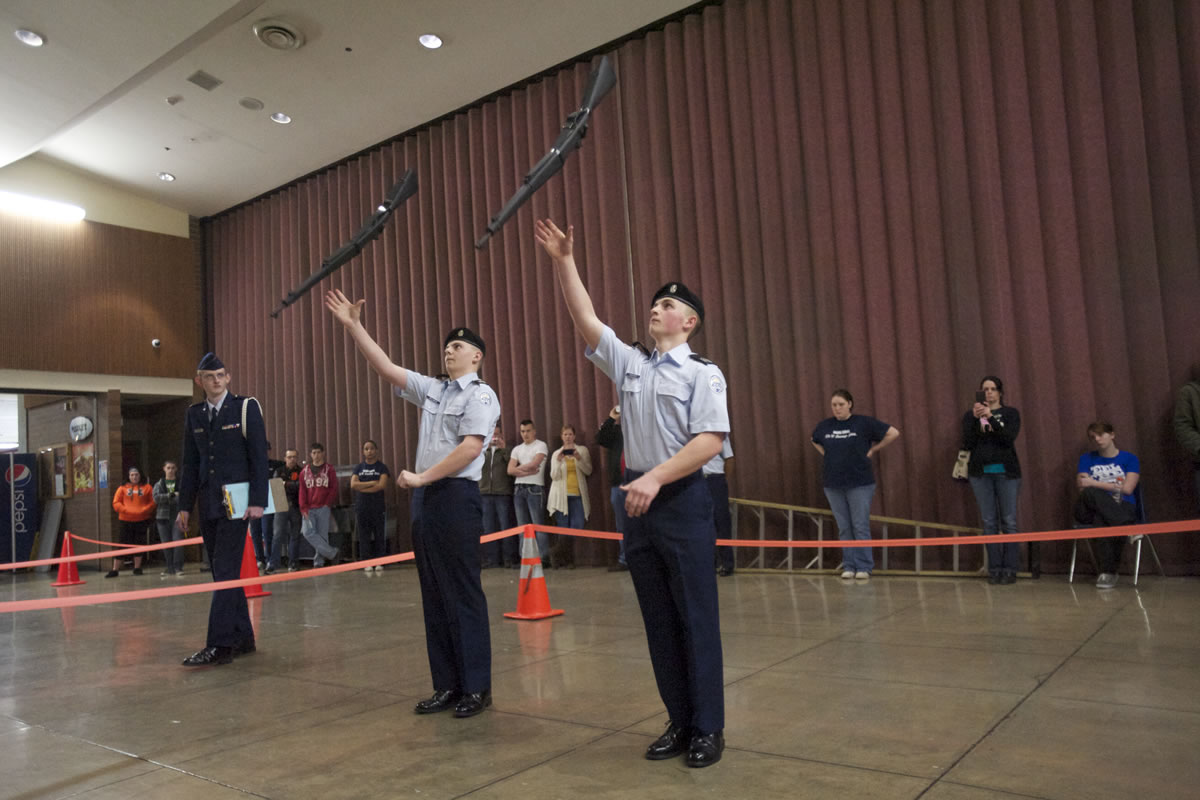 Battle Ground High School JROTC teammates, Ryan Williamson, left, and Trey Bardonski toss their rifles above their heads in the duals exhibition drill competition.