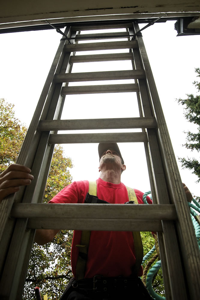Sanford Jones, a foreman with Weatherguard Inc. of Longview, makes his way up a ladder Friday to the roof of a house on Officers Row. While all the houses are at least 100 years old, &quot;The prize was the Marshall House,&quot; Jones said.