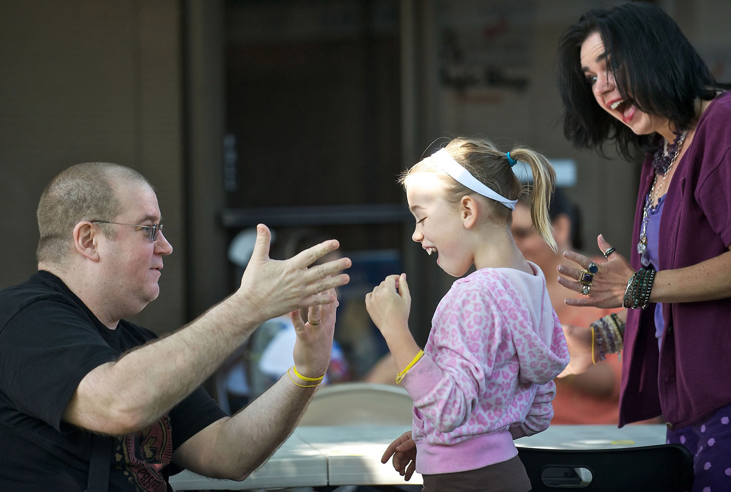 Dave Lemberg, owner of Dave's Killer Magic Shop, shows Taryn Larsen, 9, and her mother, Michele Larsen, a trick during a May 11 workshop in front of his Vancouver shop.