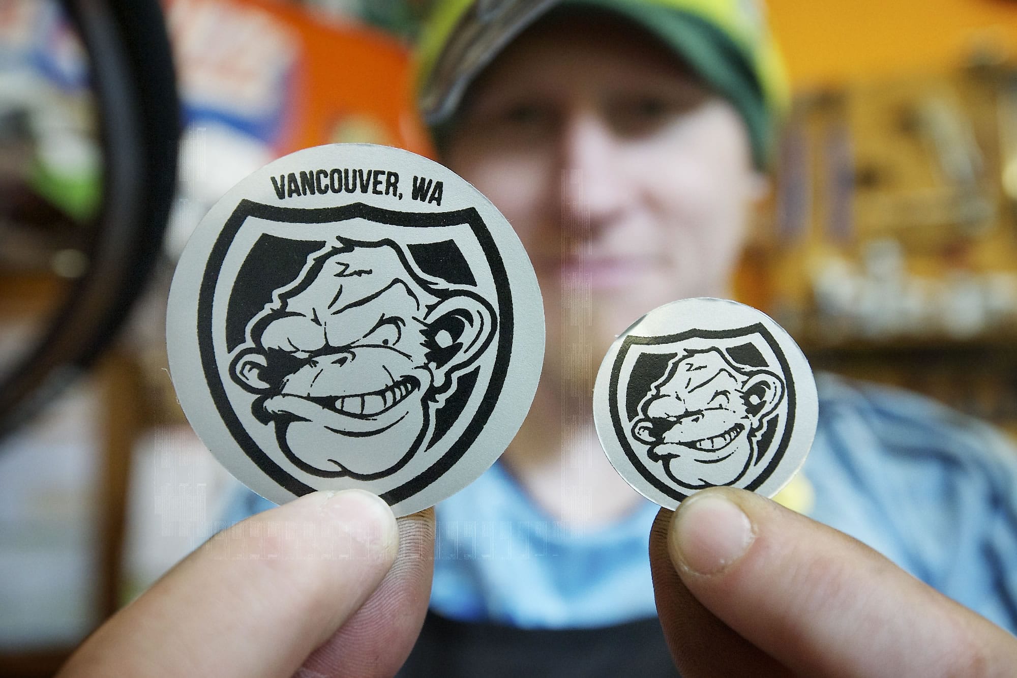 Wade Leckie, owner of Bad Monkey Bikes, holds specially designed and difficult to remove monkey shield stickers Friday at his shop in Vancouver.