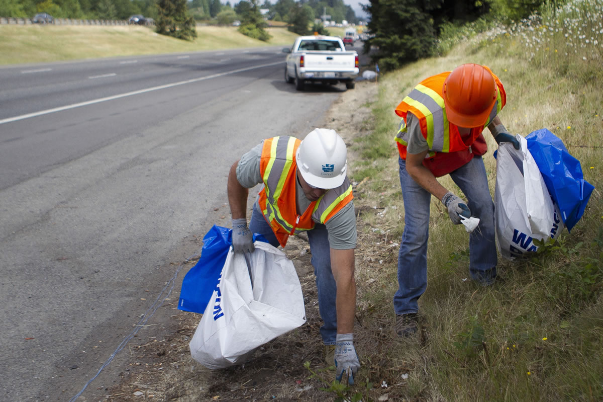 John Enslow, left, helps Ecology Youth Corps member Jake Jonas, 17, pick up trash along Interstate 5. Enslow visits different youth corps crews once a week to make sure they adhere to guidelines and safety procedures. Below: Alexandria Williams, 15, picks up trash along Interstate 5 on Monday.