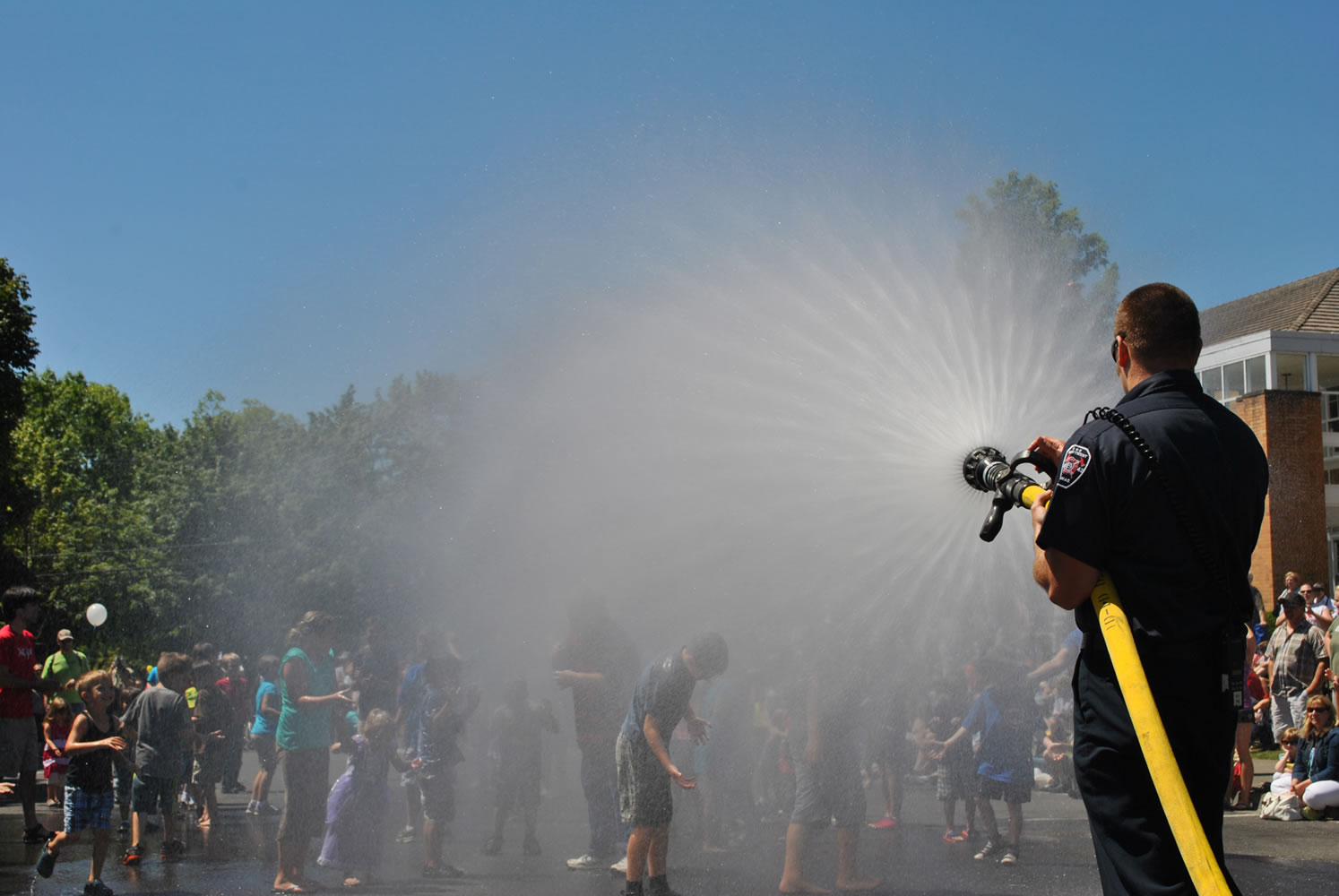 Paramedic-firefighter Chris Richardson of the Camas-Washougal Fire Department sprays kids at the Camas Days bathtub races on Saturday.