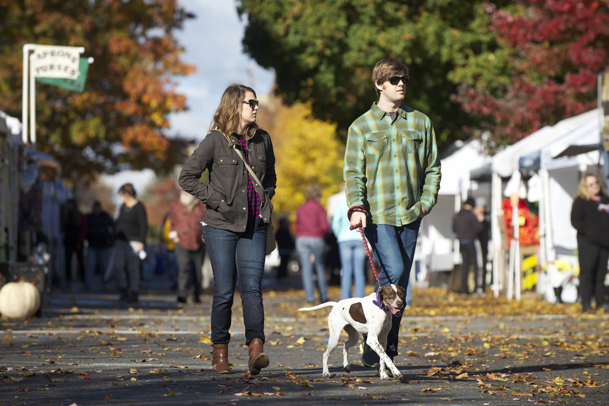Lauren Bittner, 27, left, and Ben Churchwell, 26, walk their dog Ellie, a 3-year-old German shorthaired pointer, at the Vancouver Farmers Market on Sunday, the final day of the regular season.