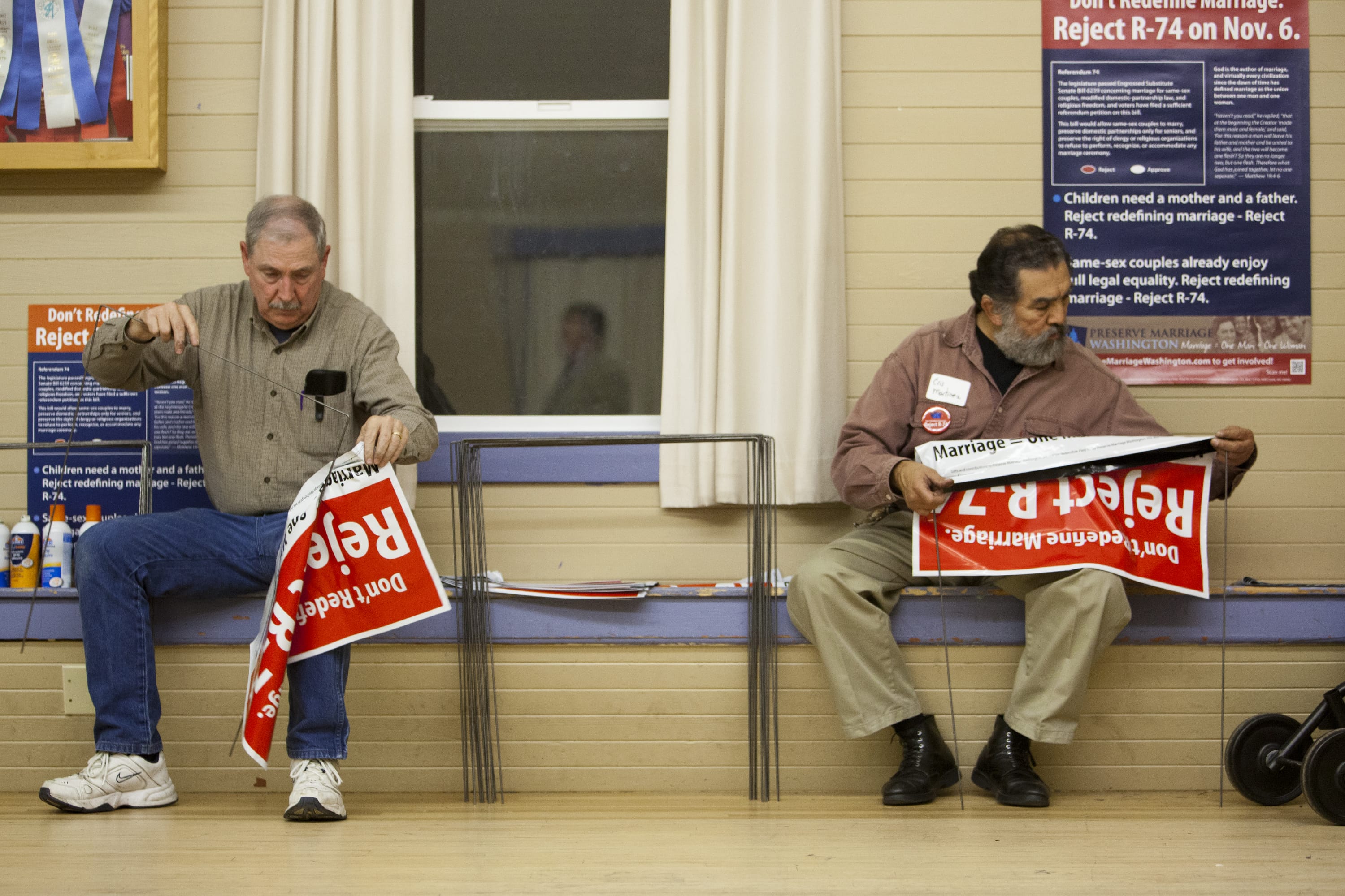 Ed Rush, left and Chris Martinez volunteer for the Reject Referendum 74 movement by putting signs together during a political rally earlier this month at Fishers Grange in Vancouver.