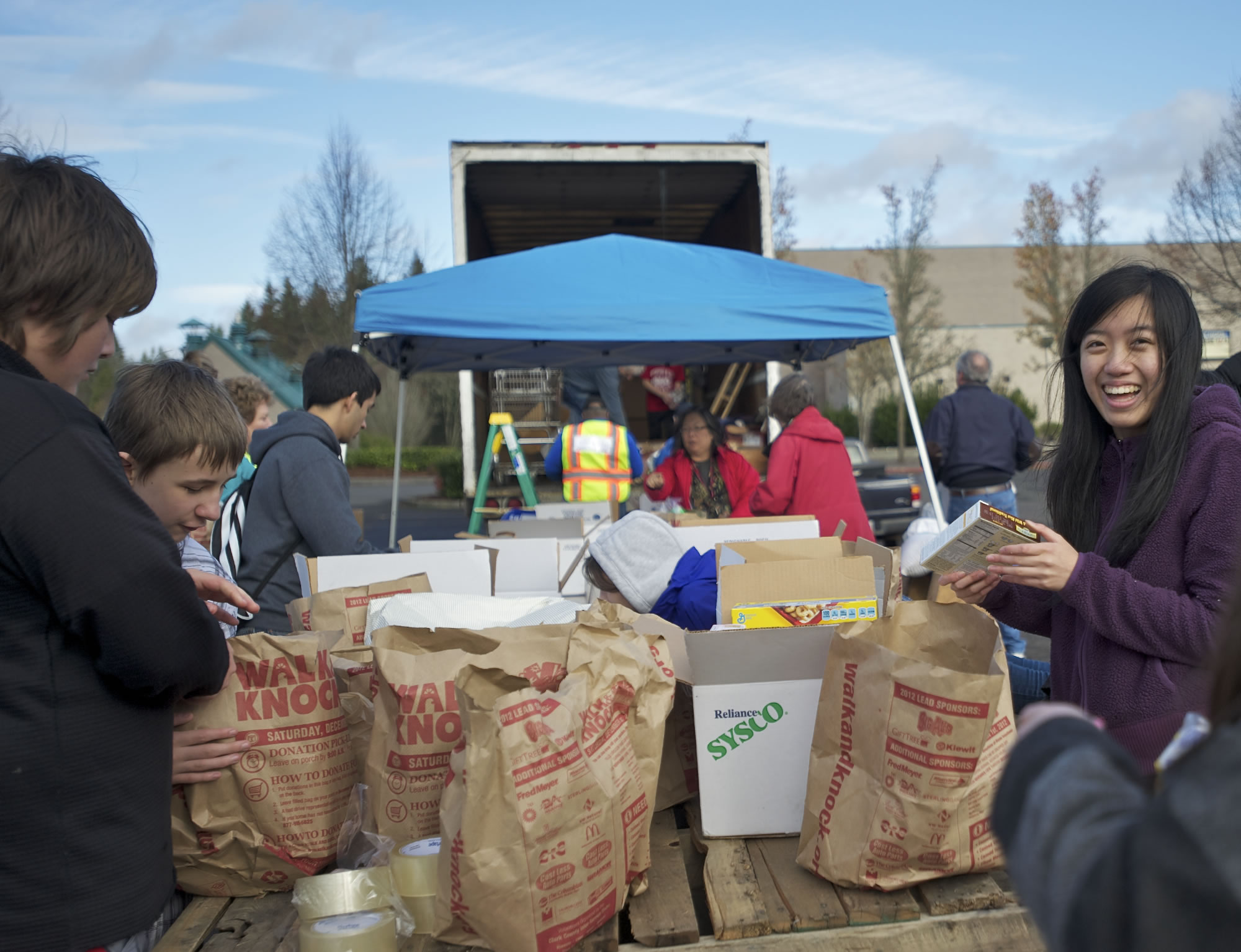 Skyview Key Club member Lauren Ho, right, 15, joins other volunteers as they sort, organize and load food donations onto a trailer at Alki Middle School on Saturday.