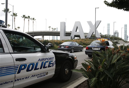 Yongda Huang Harris, 28, flying from Japan to Boston, was arrested Friday during a stopover at Los Angeles International Airport, wearing a bulletproof vest and flame-resistant pants, and traveling with a suitcase full of weapons, leg irons, a smoke grenade, a gas mask and a biohazard suit, U.S.