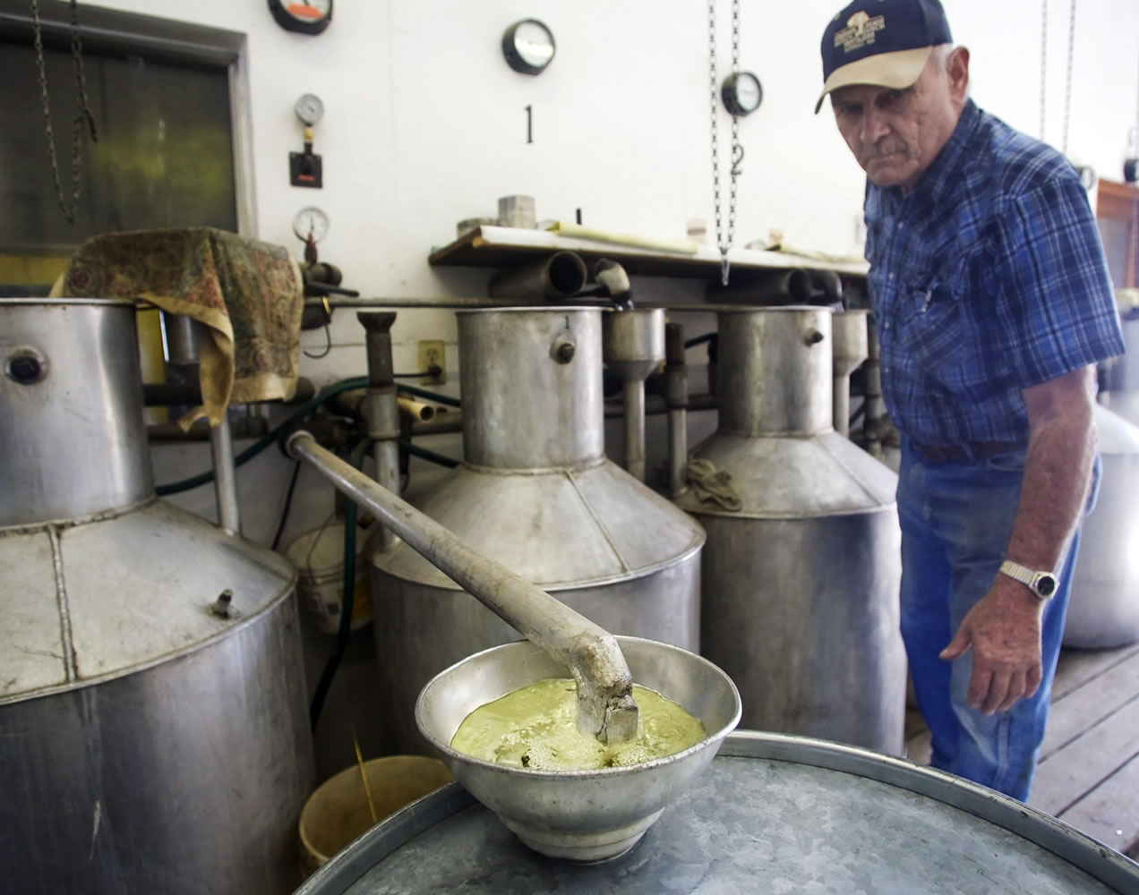 Wes Ferguson checks the progress of just-distilled pure erospicata mint oil as it flows into a drum at Ferguson Farms near Harrah in September 2010.