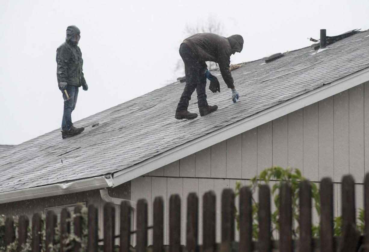 Residents survey a damaged roof one day after Battle Ground&#039;s tornado. Residents old and new couldn&#039;t think of a time they witnessed such carnage in town.