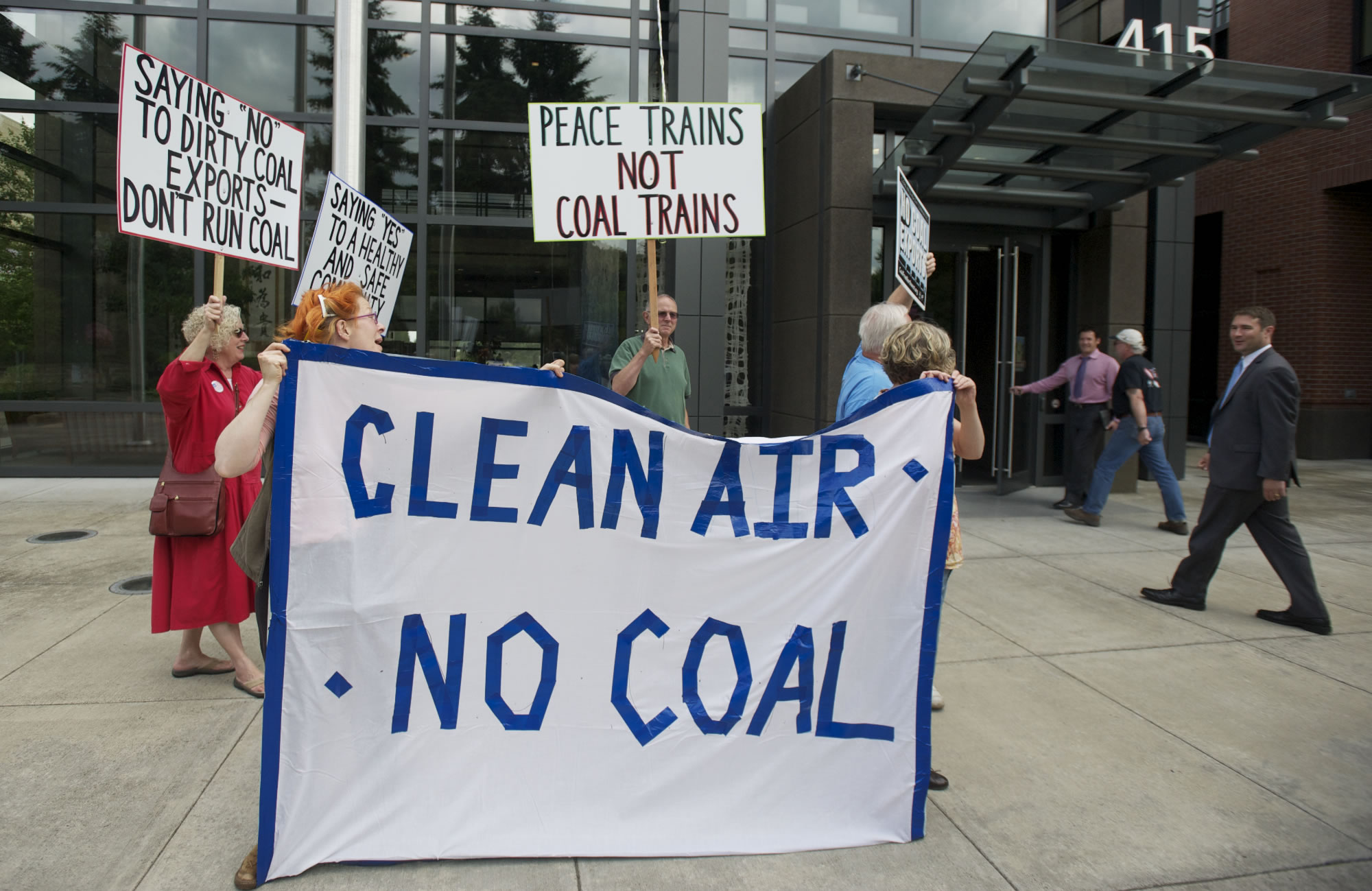 Members of anti-coal group Beyond Coal greet Vancouver Mayor Tim Leavitt, holding the door, and Councilor Bart Hansen, far right, as they enter City Hall on July 2.