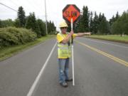 Flagger Rusty Goodson directs traffic near a utility works project on Northeast 72nd Avenue.