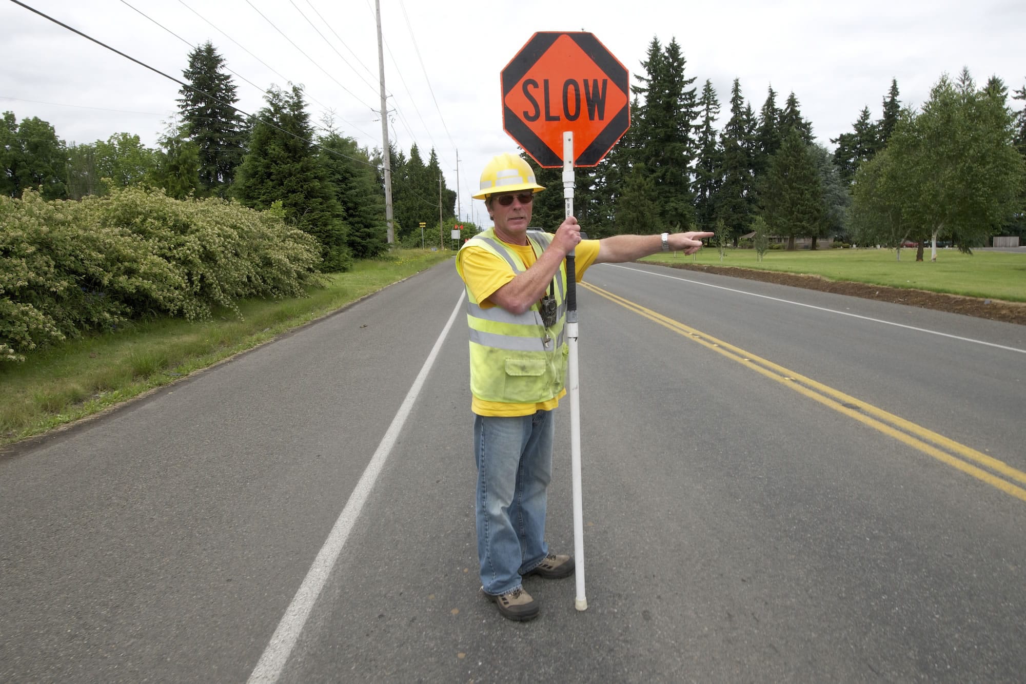 Flagger Rusty Goodson directs traffic near a utility works project on Northeast 72nd Avenue.