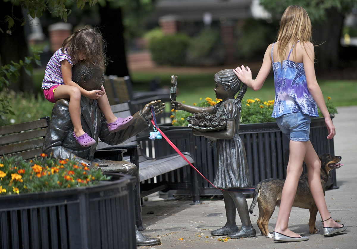 Lucy Tibbits, right, 11, of Vancouver, her sister Christianna Tibbits, 5, and their dog, Charlie, interact with a piece of public art at Esther Short Park in August 2012.