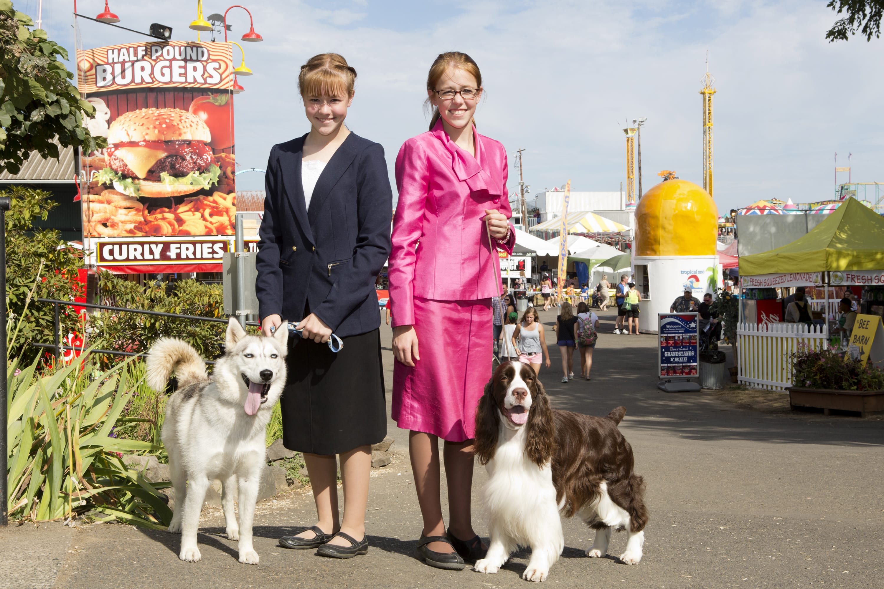 Hailey, left, with Aspyn,  and Heidi Christenson, with J,  are everywhere at the Clark County Fair. Here they pose on the midway with the dogs they show, wearing clothing they constructed and modeled.