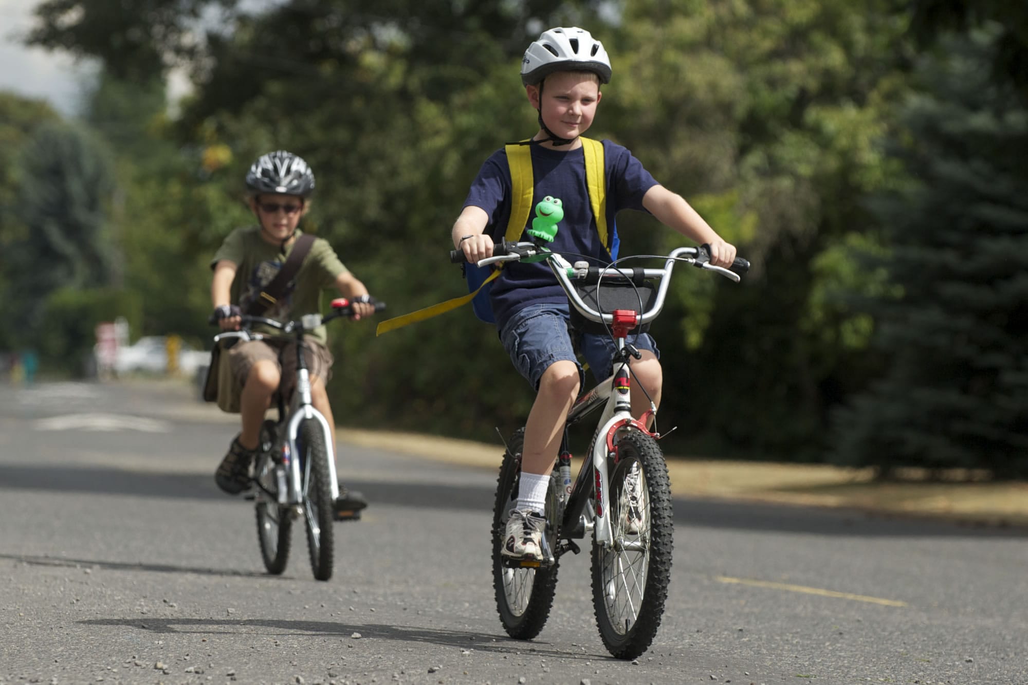 Nine-year-old pals Grant Myers, in front,  and Luke Seeley, behind, pedal Southeast Middle Way to deliver copies of The Weekly Neighbor. &quot;I like delivering real papers,&quot; said Seeley.