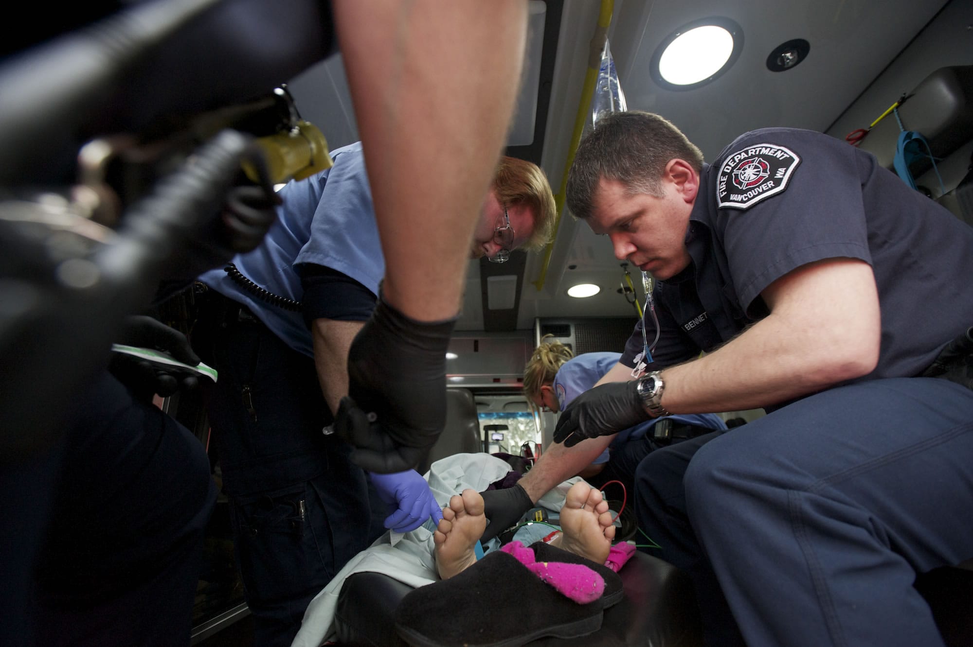 Vancouver firefighter-paramedic Mark Bennett, right, tries to find a usable vein on a female patient who collapsed March 1 during a cigarette break outside Lifeline Connections, where she was in treatment for heroin addiction.