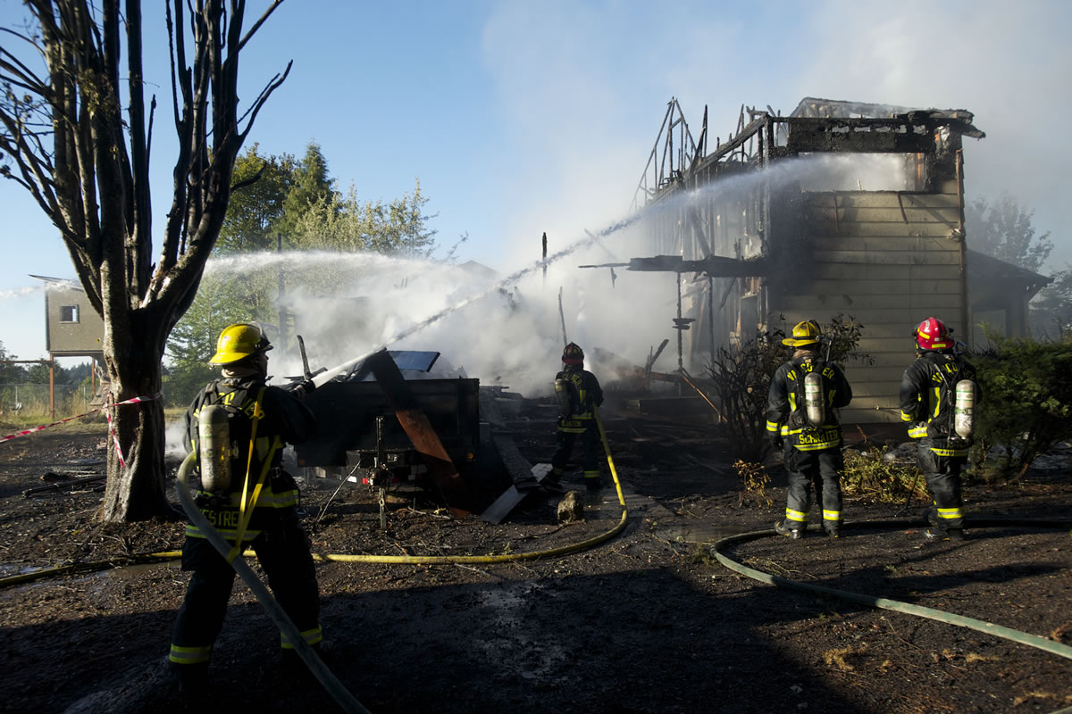 Photos by Steven Lane/The Columbian
Firefighters battle the blaze that destroyed an unoccupied house Friday evening off Northwest 119th Avenue in Felida.