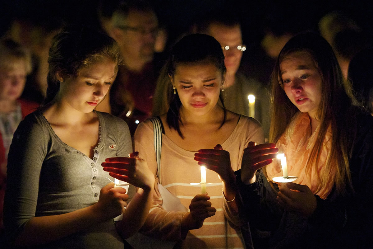 Ridgefield High School students Karlie Williams, 14, from left, Tiahna Duprat, 14, and Sierra Lavalley, 15, hold candles in honor of Tanner Trosko, 17, during a Saturday evening vigil in Ridgefield.