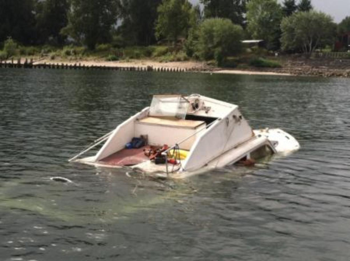 A cabin cruiser sits partially submerged after it took on water and was abandoned near Kelley Point in the Columbia River on Monday.