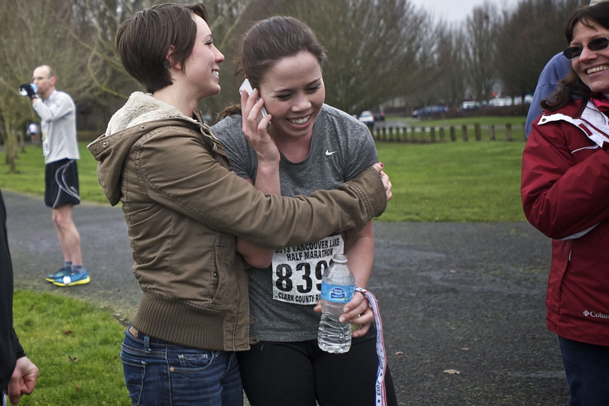 Shannon Porter gets a hug from her sister Georgia Porter while talking on the phone with her other sister Sarah Crouch at the finish line of the Vancouver Lake Half Marathon after finishing first for the women.
