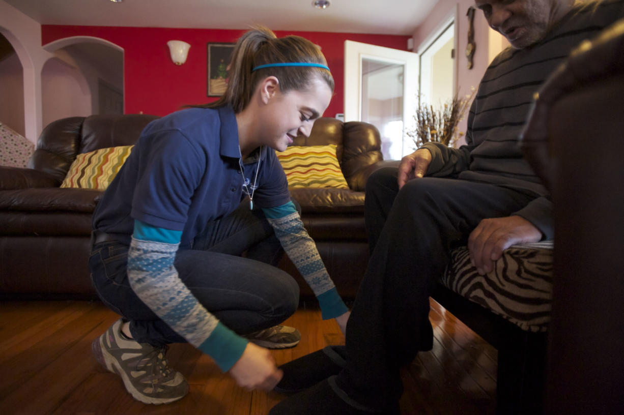 Chelsey Swank, a caregiver for Comfort Keepers, helps client Narayan Prasad in his home.