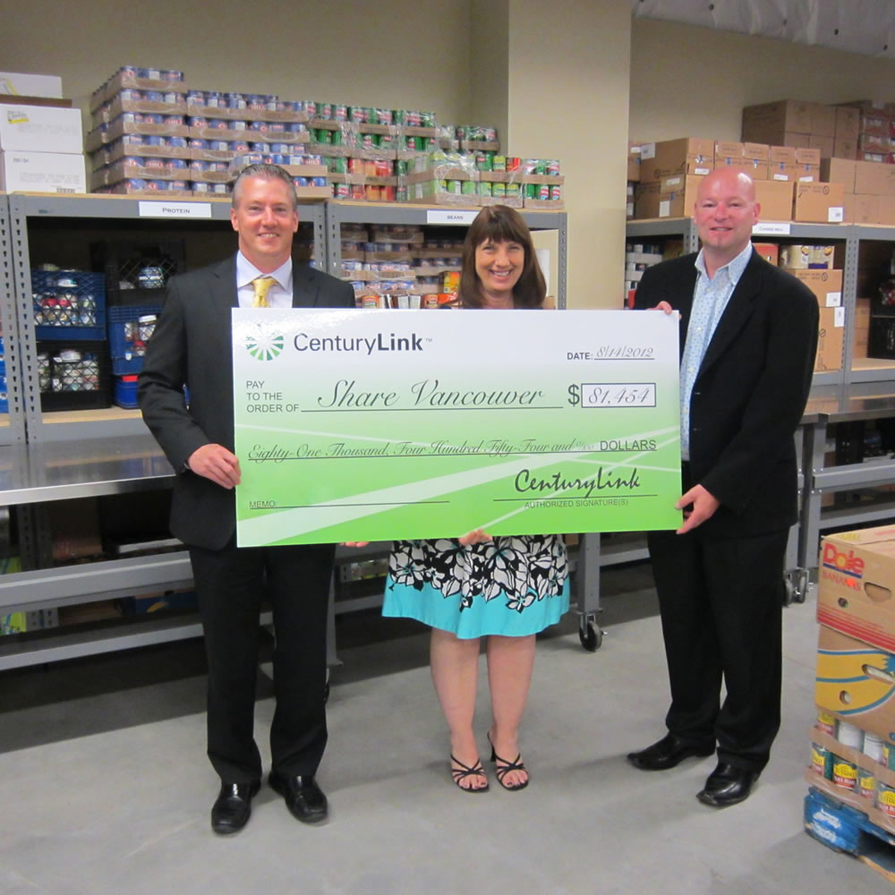 Meadow Homes: CenturyLink Vice President Christopher Denzin, left, and Marketing Manager Martin Flynn present big bucks to Share Executive Director Diane McWithey.