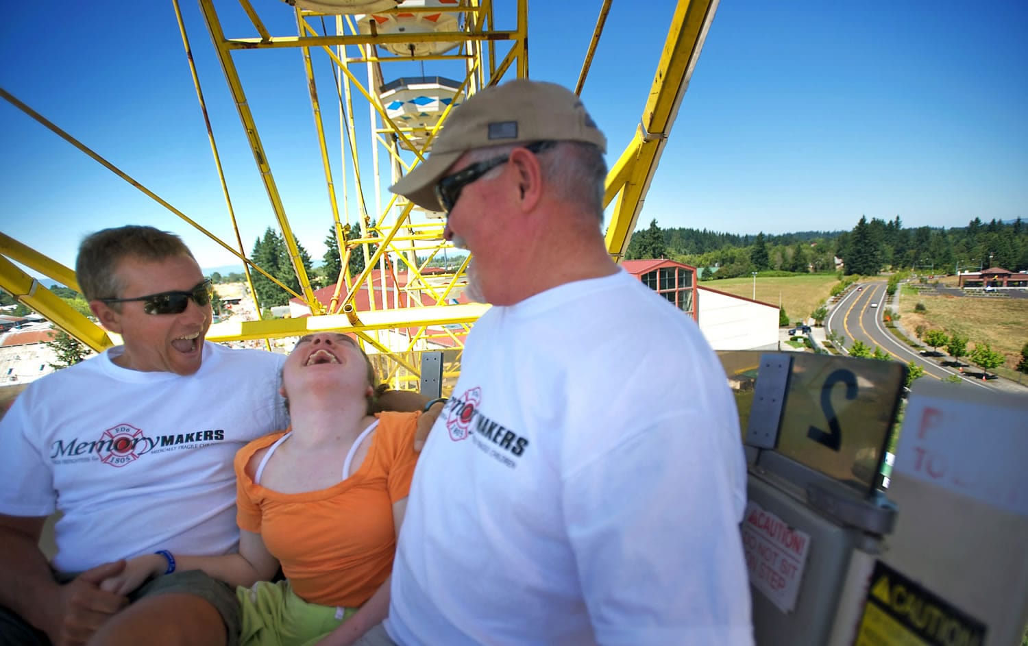 Melissa Macy, 18, of Portland, rides the Ferris wheel on Tuesday with firefighter Jeff Van Laeken, left, and retired firefighter Roy Alvstad.